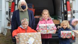 Kita-Leiterin und Kinder packen Päckchen in einen Transporter