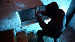 Einbrecher an einem Kellerfenster