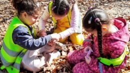 KInder sitzen auf dem Waldboden