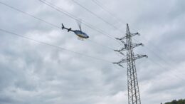 Hubschrauber fliegt über eine Freileitung