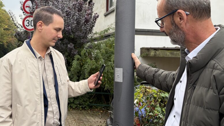 Bürgermeister scannt QR-Code an einer Straßenaterne
